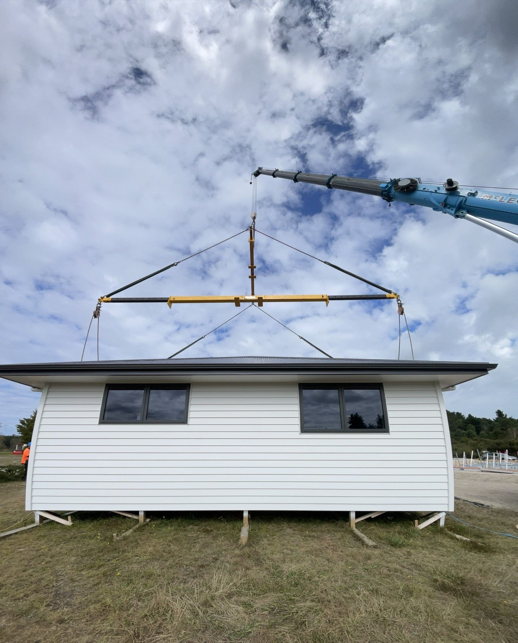 Mobile crane lifting a house module with a spreader bar rig
