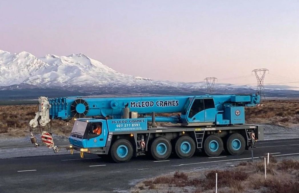 Mobile crane on the road with mountains in the background